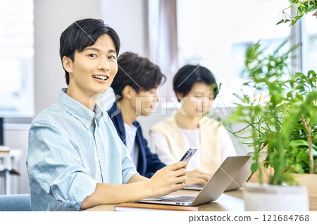 Young male businessman in plain clothes working in the office Young male businessman in plain clothes working in the office 121684768
