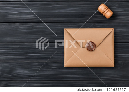 Elegant envelope with wax seal and wooden stamp on dark wooden table 121685217
