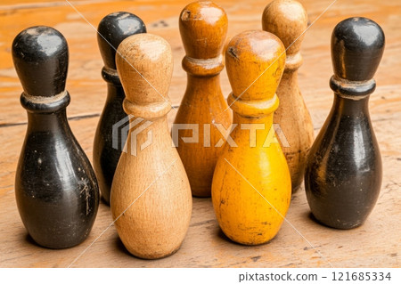 Vintage wooden bowling pins arranged on a rustic wooden table in soft light 121685334