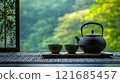 Tea ceremony setup with a kettle and cups surrounded by lush greenery in a tranquil setting 121685457