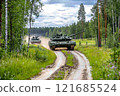 Military tanks maneuvering through a forested area in a military training exercise during daylight hours 121685524