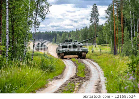 Military tanks maneuvering through a forested area in a military training exercise during daylight hours Military tanks maneuvering through a forested area in a military training exercise during daylight hours 121685524