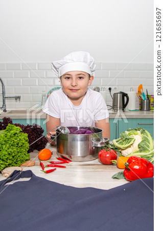 A cute little boy in a chef's costume cooks food with emotions 121685697