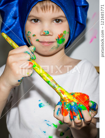 Smiling young boy with paint on his hands and face 121685771