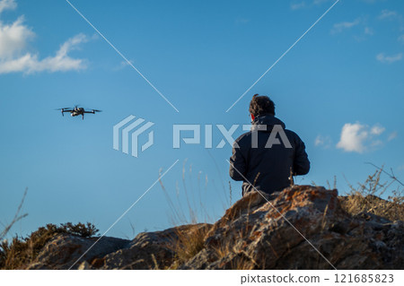 Drone pilot operating on rocky terrain during sunny weather outdoors 121685823