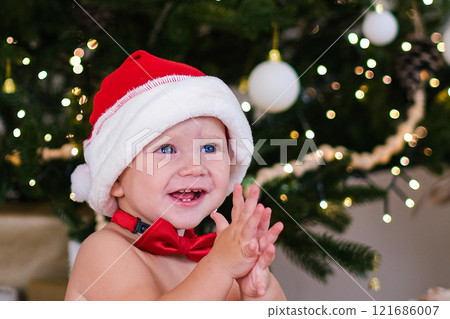 Christmas baby in santa hat sitting and laughing 121686007