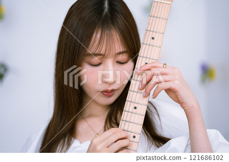 拿著電吉他的長髮年輕女子 121686102