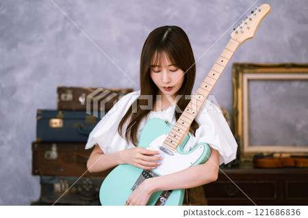 拿著電吉他的長髮年輕女子 121686836