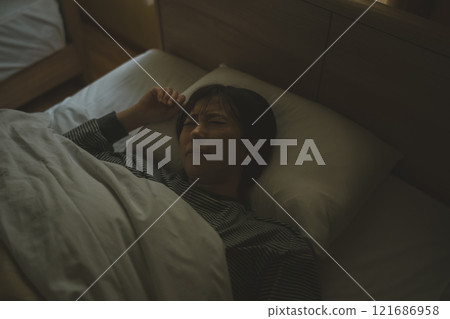 Young woman sleeping painfully in bed 121686958