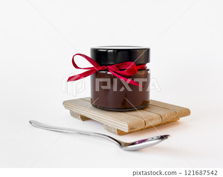 Elegant chocolate jar with red ribbon on wooden stand 121687542