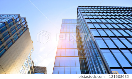 Looking up at the commercial buildings in downtown. Modern office building against blue sky. Windows of a modern glass building. Looking up at the commercial buildings in downtown. Modern office building against blue sky. Windows of a modern glass building. 121688683