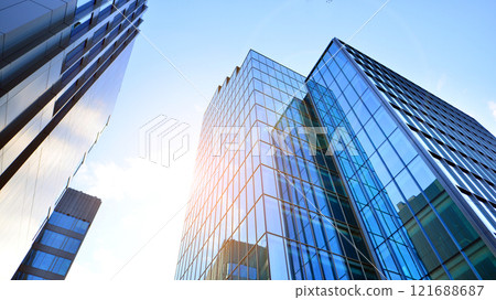 Looking up at the commercial buildings in downtown. Modern office building against blue sky. Windows of a modern glass building. 121688687