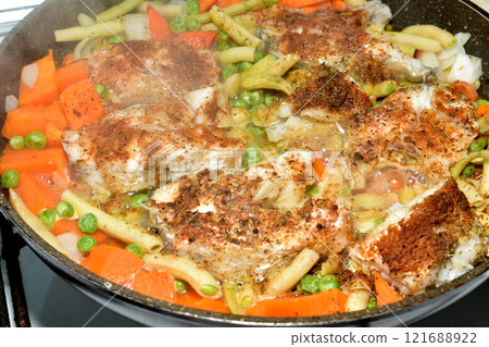 Cod fish is cooked in a frying pan. 121688922