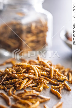 Dried salted worms. Roasted mealworms on kitchen table. 121689728