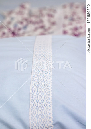 Blue fabric with intricate white lace detail and floral patterned backdrop. 121689830