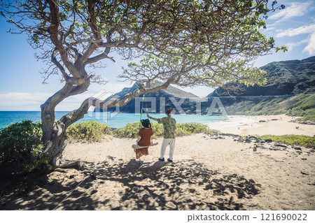 An elderly couple watches the ocean from a tree swing on the east coast of Hawaii An elderly couple watches the ocean from a tree swing on the east coast of Hawaii 121690022