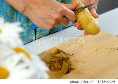 Woman peeling boiled potato cooking dish, salad, garnish on kitchen using knife. Woman peeling boiled potato cooking dish, salad, garnish on kitchen using knife. 121690026