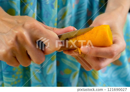 Woman peeling baked carrot cooking dish, salad, garnish on kitchen using knife. Woman peeling baked carrot cooking dish, salad, garnish on kitchen using knife. 121690027
