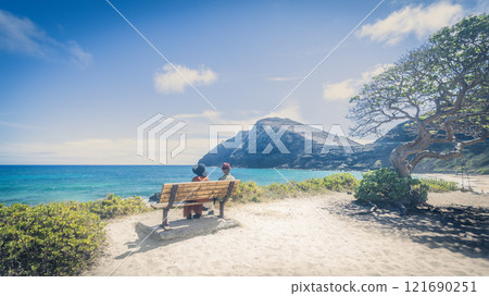 一對老夫婦在夏威夷東海岸的海灘長椅上眺望大海 121690251