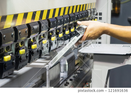 Close up the bending machine operator hold the sheet metal parts. Close up the bending machine operator hold the sheet metal parts. 121691636