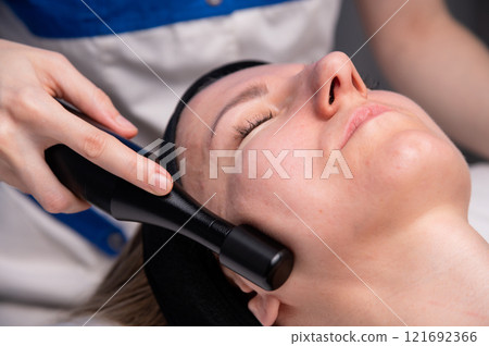 Woman undergoing skin tightening by activating a natural process. A cosmetologist performs a skin rejuvenation procedure in a spa. Aesthetic medical cosmetology Woman undergoing skin tightening by activating a natural process. A cosmetologist performs a skin rejuvenation procedure in a spa. Aesthetic medical cosmetology 121692366