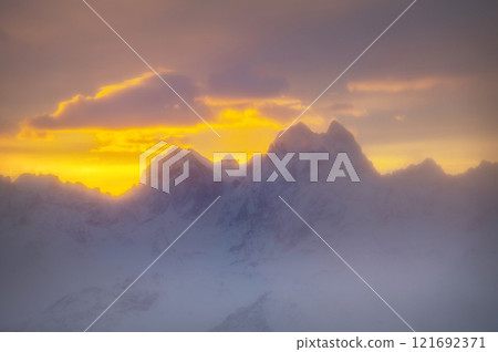 vibrant sunrise with a spectrum of colours merging seamlessly across the sky. Fiery orange and gold dominate the horizon, fading to soft pinks, purples and pale blues as the sun rises 121692371