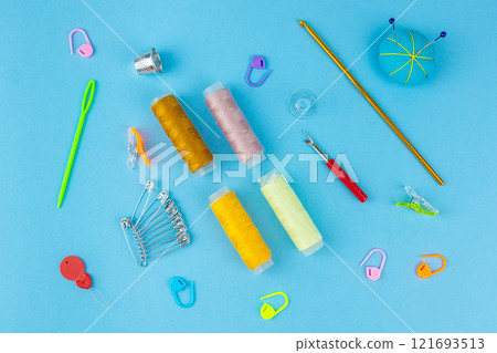 Sewing accessories on a blue bed background. Sewing accessories on a blue bed background. 121693513
