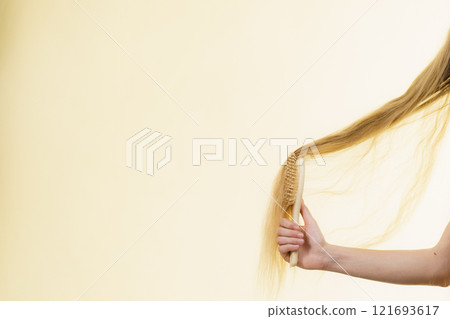 Blonde girl brushing her long hair 121693617