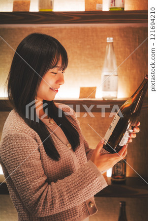 選擇清酒的年輕女性[攝影合作：新潟當地清酒優質SAKE Kura KURA] 121694210