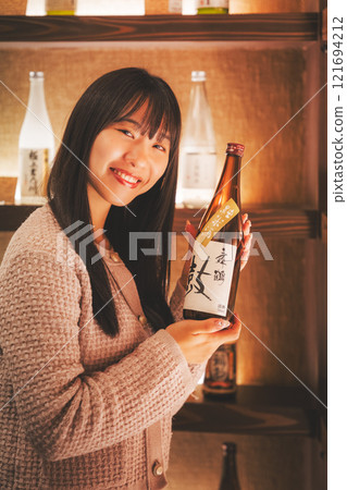 A young woman choosing Japanese sake [Photo courtesy of Niigata Jizake Premium SAKE Kura KURA] 121694212