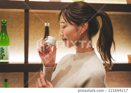 品嚐日本清酒的年輕女子[照片合作：新潟當地清酒特級SAKE Kura KURA] 121694217