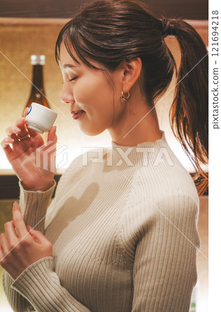 A young woman tasting sake [Photo courtesy of Niigata Jizake Premium SAKE Kura KURA] 121694218