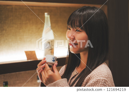 A young woman tasting sake [Photo courtesy of Niigata Jizake Premium SAKE Kura KURA] 121694219