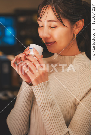 A young woman tasting sake [Photo courtesy of Niigata Jizake Premium SAKE Kura KURA] 121694227