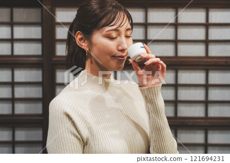 A young woman tasting sake [Photo courtesy of Niigata Jizake Premium SAKE Kura KURA] 121694231