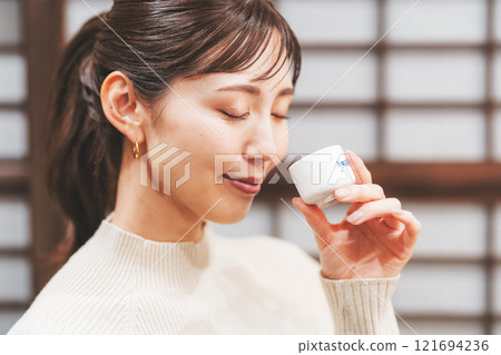 A young woman tasting sake [Photo courtesy of Niigata Jizake Premium SAKE Kura KURA] 121694236