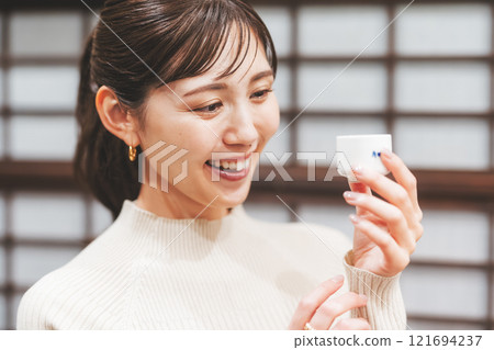 A young woman tasting sake [Photo courtesy of Niigata Jizake Premium SAKE Kura KURA] 121694237