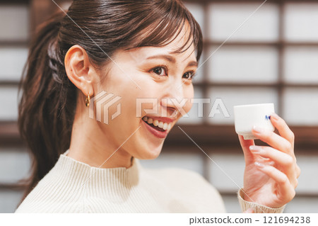 A young woman tasting sake [Photo courtesy of Niigata Jizake Premium SAKE Kura KURA] 121694238