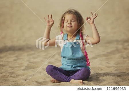 child doing yoga on the beach in Denmark child doing yoga on the beach in Denmark 121696083