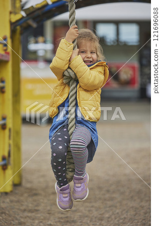 Charming child climbs a rope at a playground in Denmark 121696088