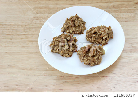 Homemade oat and banana cookies on the white plate on the wooden table, dessert for vegan 121696337