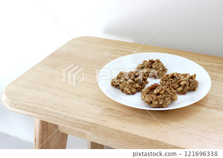 Homemade oat and banana cookies on the white plate on the wooden table, dessert for vegan Homemade oat and banana cookies on the white plate on the wooden table, dessert for vegan 121696338