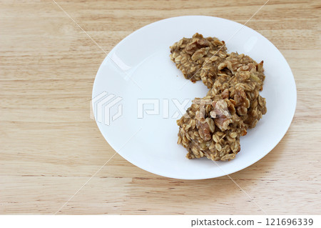 Homemade oat and banana cookies on the white plate on the wooden table, dessert for vegan 121696339