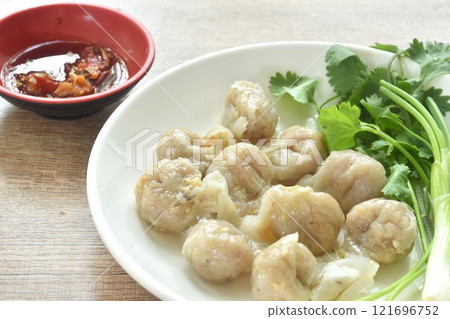 steamed fish dumpling with parsley and spring onion on plate dipping spicy sour sauce  121696752