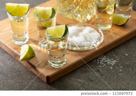 Tequila with sea salt and lime slices on a cutting board. 121697072