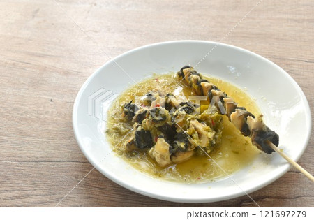 baking cherry or golden apple snail stabbing wooden stick dressing Thai spicy seafood sauce on plate 121697279