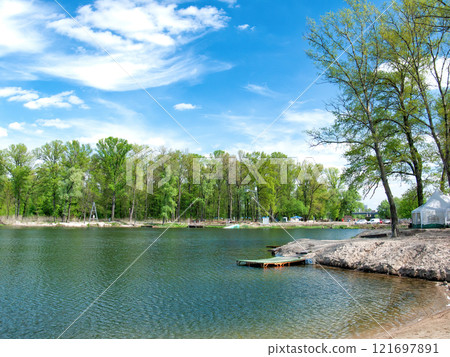 Tranquil lakeside retreat with clear skies and lush green scenery 121697891