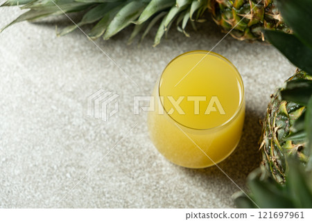 Pineapple juice in a glass among fresh pineapple fruit close-up. 121697961