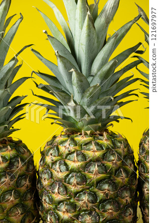 Ripe fresh pineapples on a yellow background close-up. Ripe fresh pineapples on a yellow background close-up. 121697977