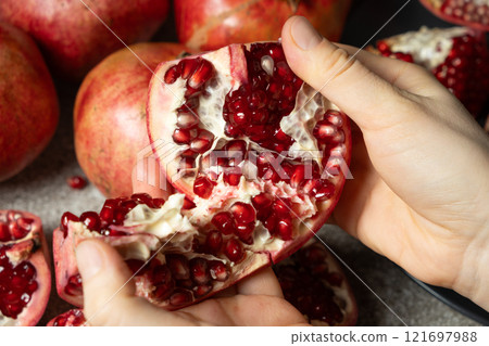 Hands open the pomegranate, separation into parts, pomegranates grains Hands open the pomegranate, separation into parts, pomegranates grains 121697988